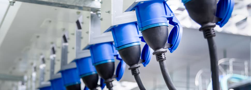 Row of blue industrial electrical connectors plugged into a power distribution system in a data centre